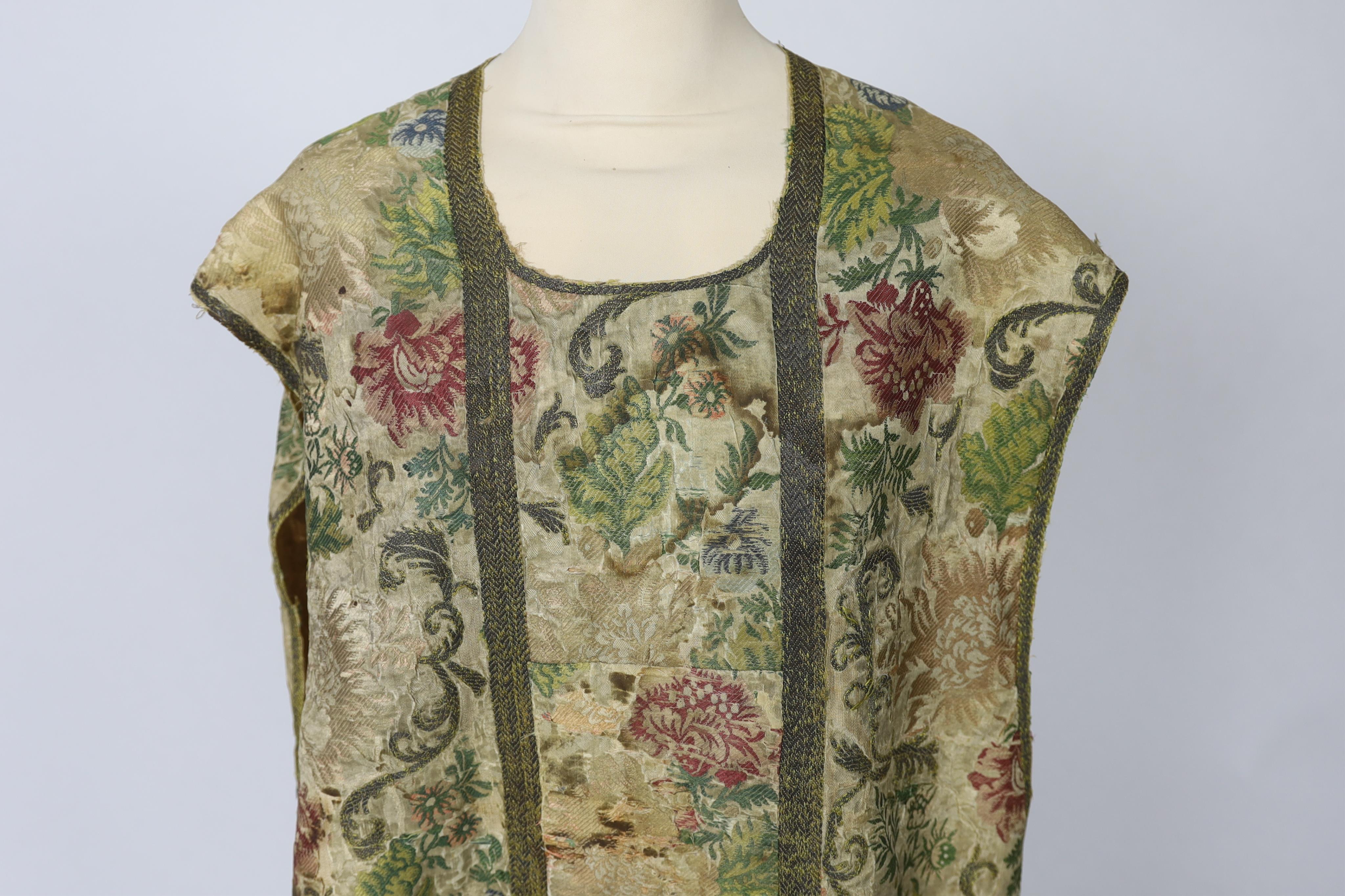 A late 18th century continental, possibly French, silk multi coloured and metallic brocade chasuble, lined with thick linen, edged and panelled with a thick metallic braid, 99cm long